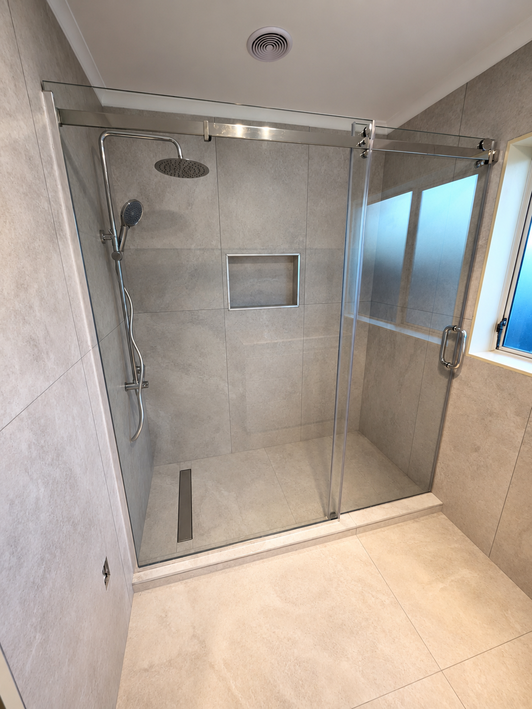 Newly renovated walk-in shower with frameless glass, rainfall showerhead, and elegant tilework