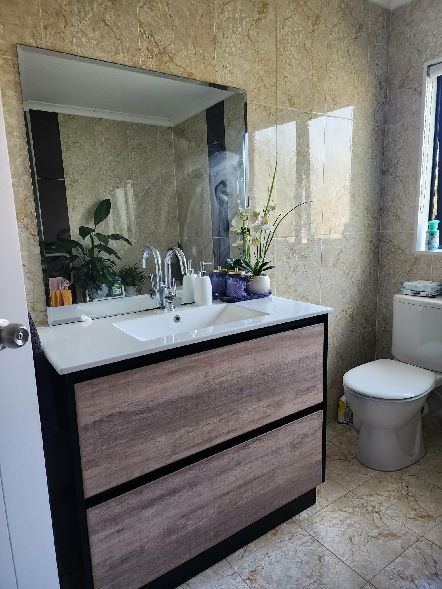 Luxury ensuite bathroom renovation featuring twin vanity, backlit mirrors, and matte black fixtures