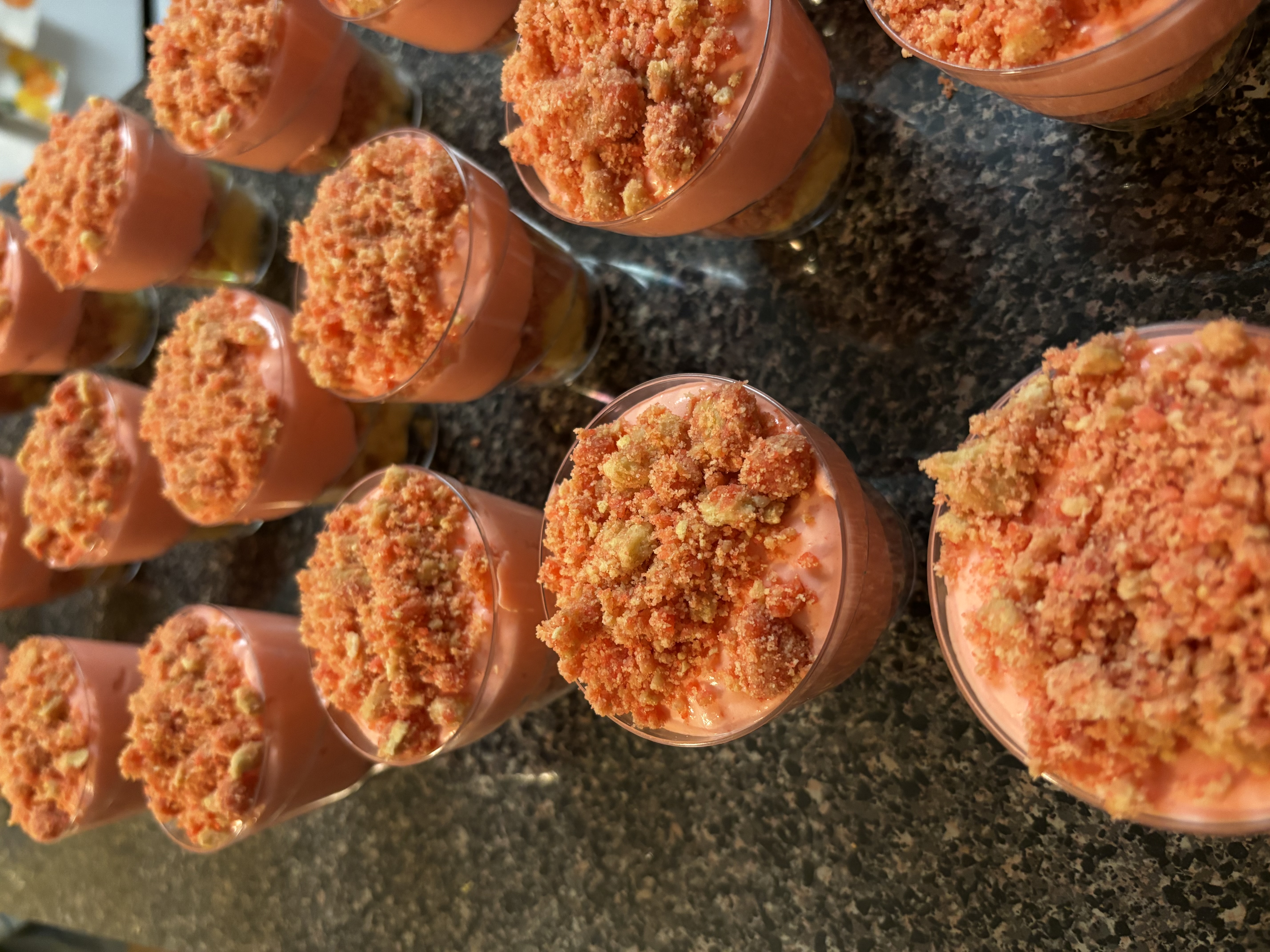 A single serving cup of strawberry crumble pudding topped with fresh strawberries and whipped cream.