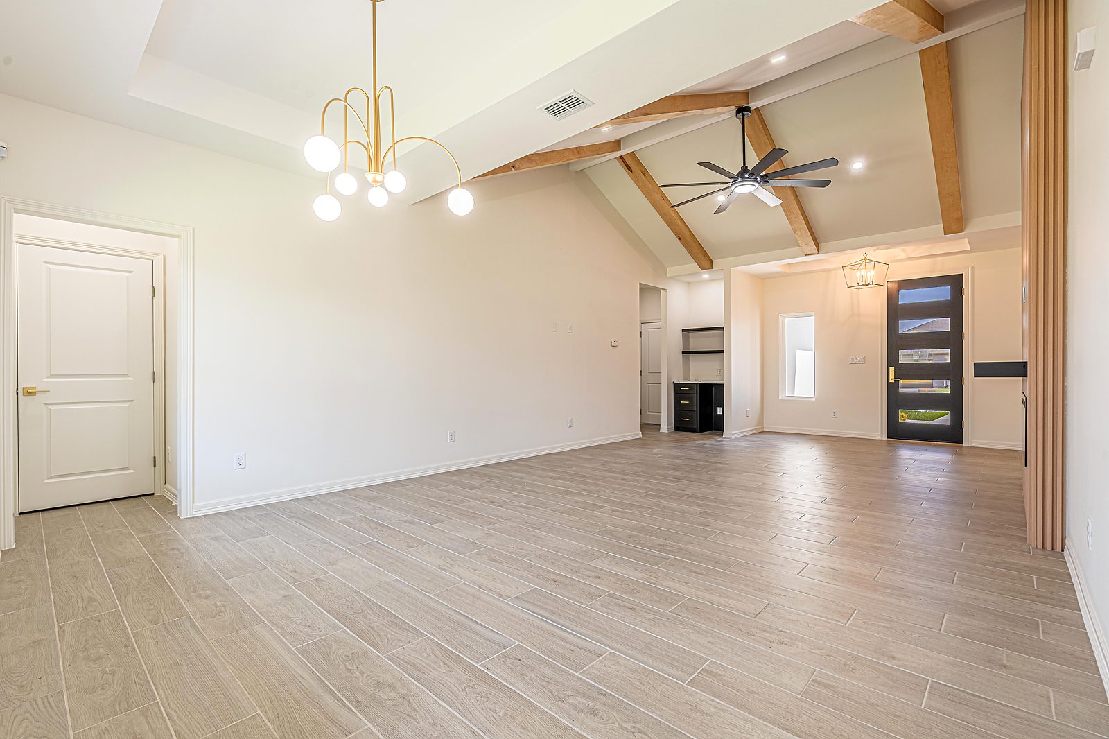 Open living room with vaulted ceiling, exposed beam, and designer chandelier