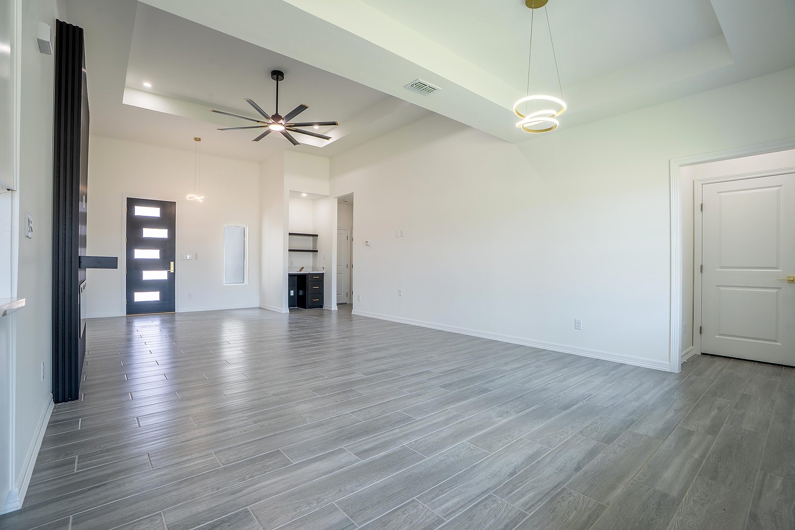 Entry and living area with black slat-wall feature and designer pendants