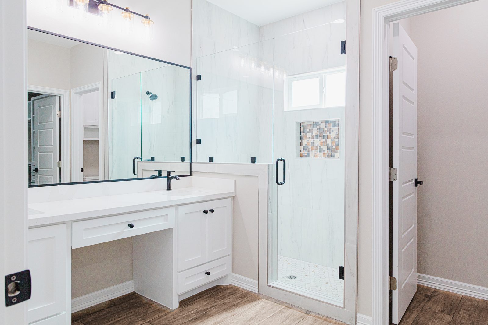 Primary bathroom with marble walls, framed glass shower, and mosaic niche