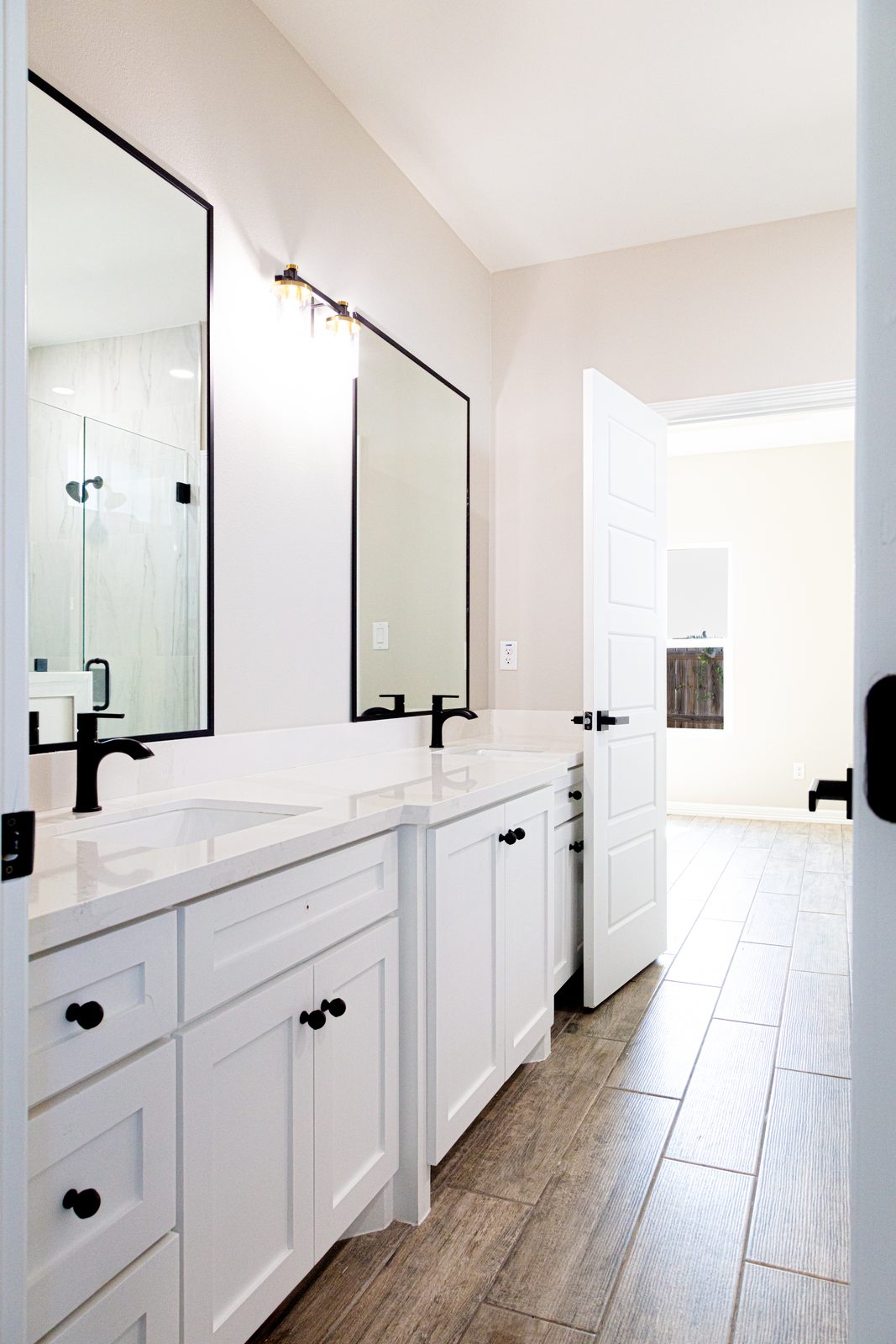 Bathroom with white double vanity, matte-black fixtures, and wood-look tile
