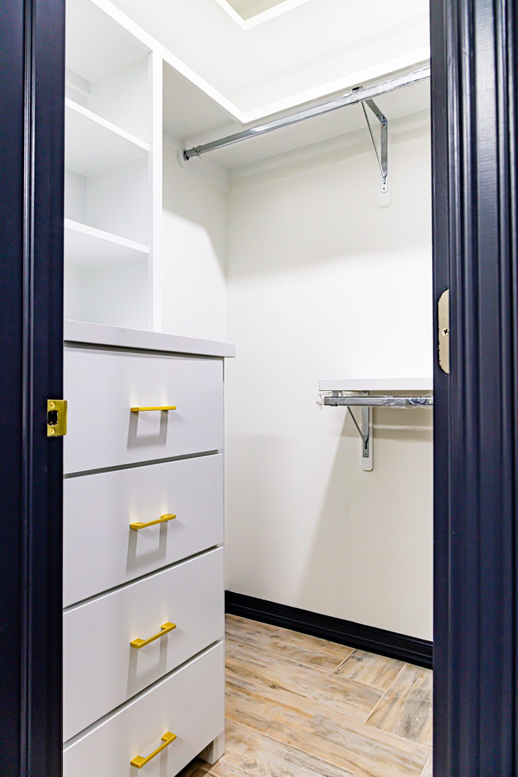 Walk-in closet with navy trim and gold pulls