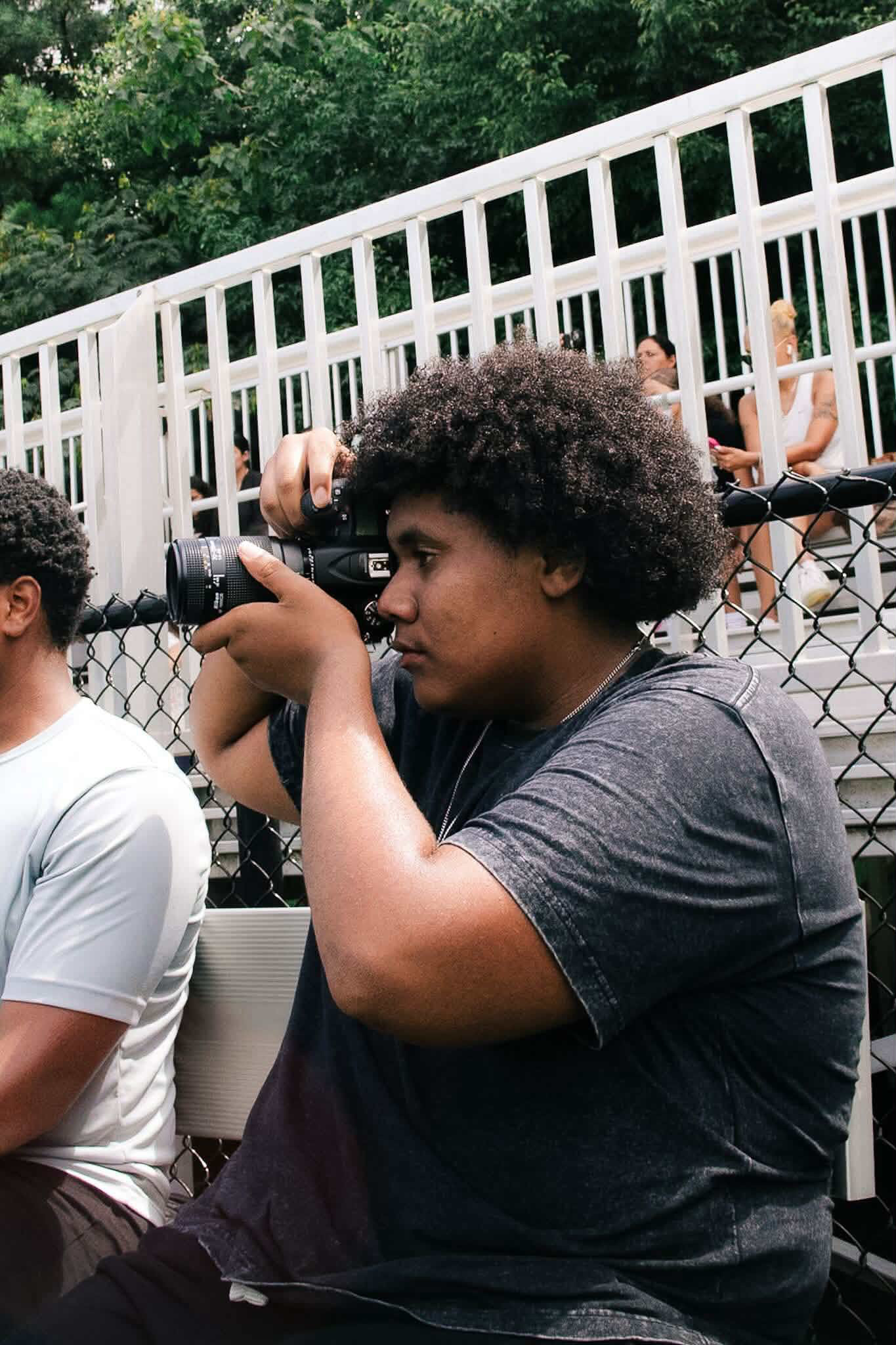 Sports photographer Bryce King with camera on a football sideline