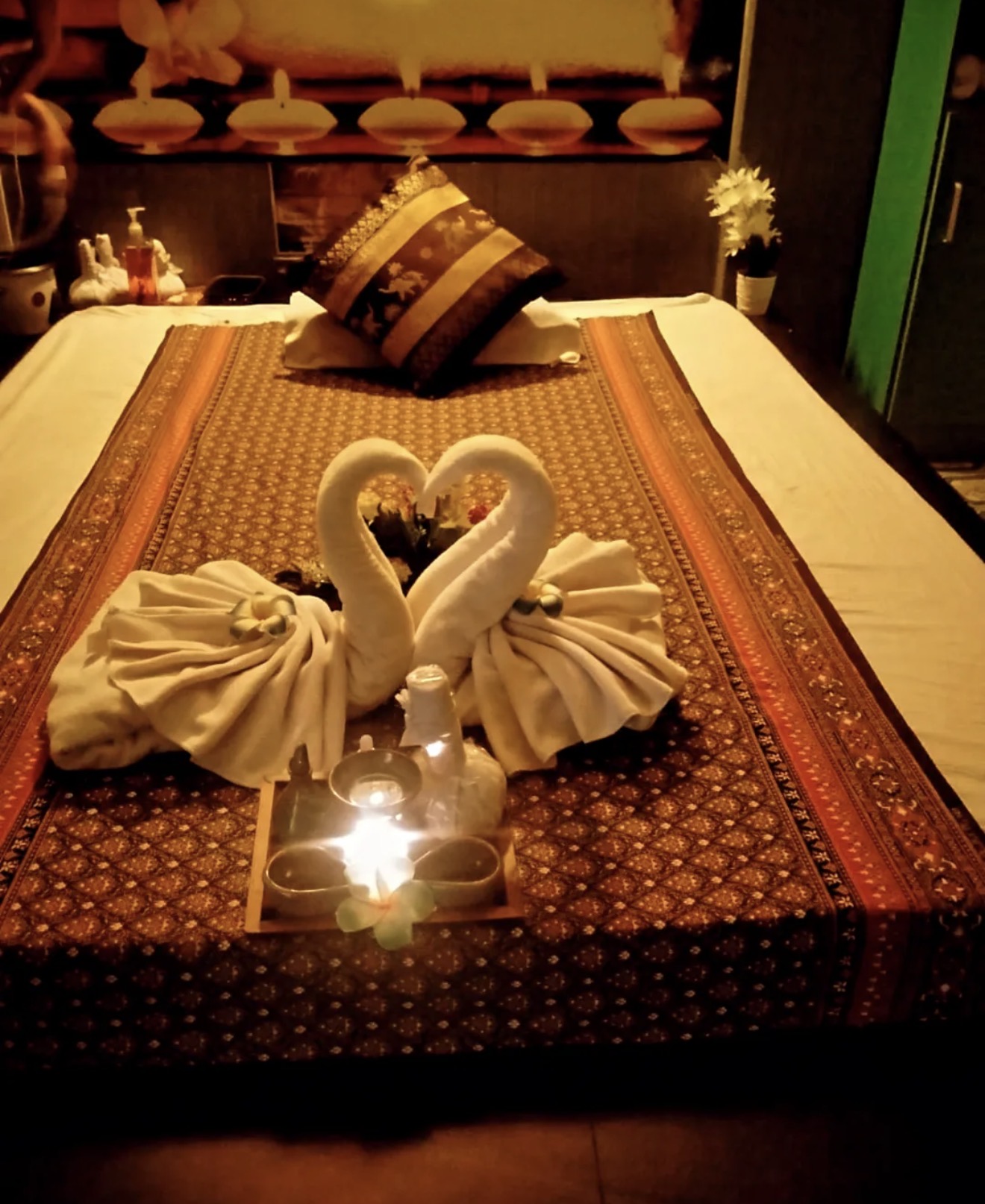 Serene luxury spa ambiance with glowing candles, white orchids, warm walnut wood tones, and aromatic essential oils bathed in soft golden light — a sanctuary for women's relaxation