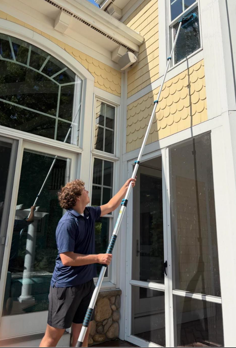Friendly professional window washer cleaning a residential window
