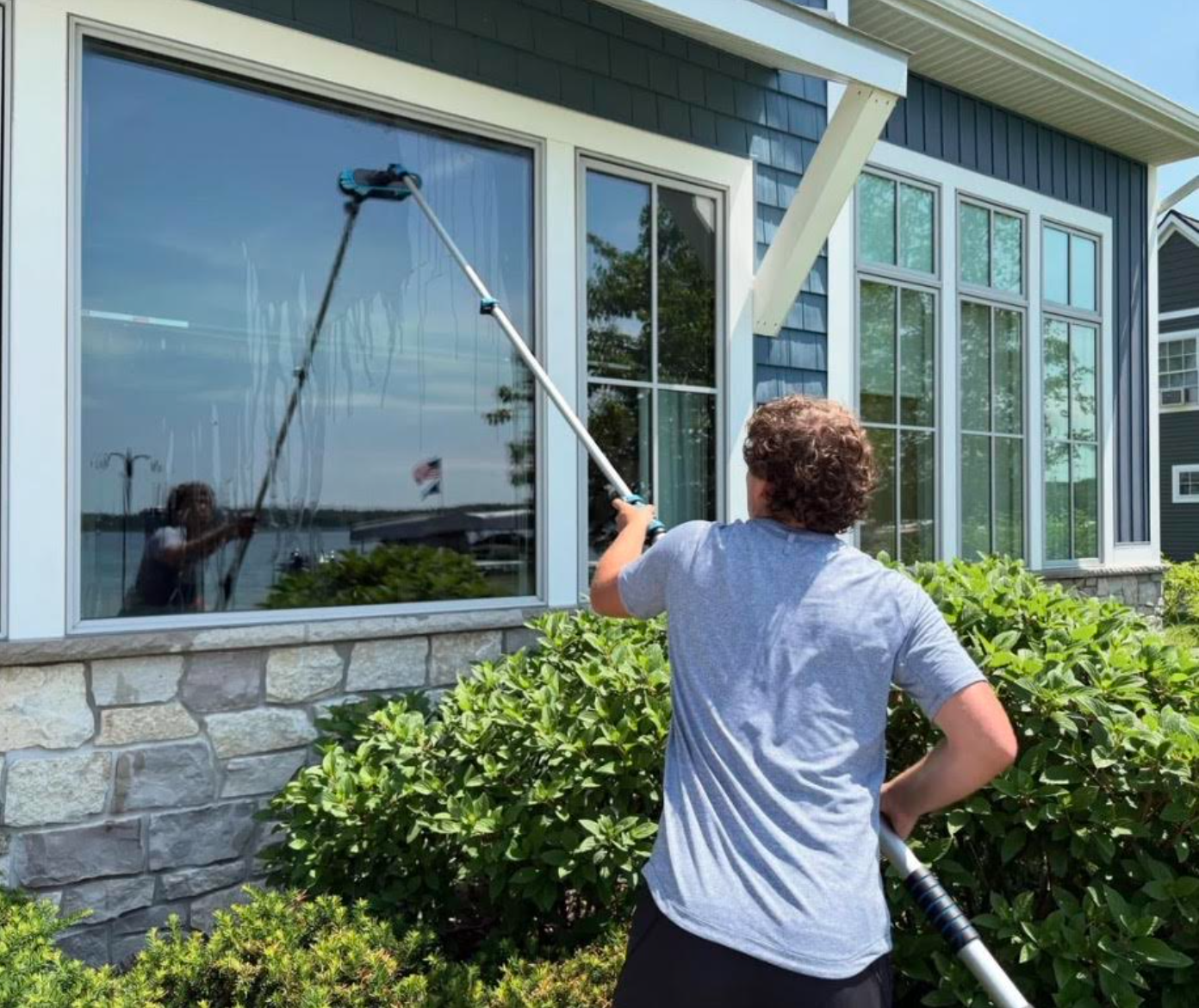 Professional window washer revealing a sparkling clean glass reflection on a beautiful residential home