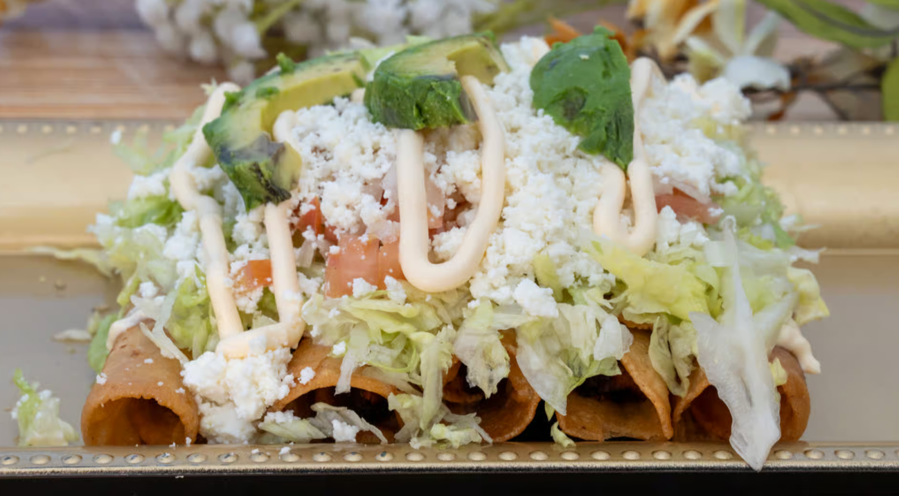 Massive fully loaded authentic Mexican grilled chicken burrito cut in half, revealing colorful layers of seasoned grilled chicken, fluffy Spanish rice, black beans, melted cheese, fresh pico de gallo, creamy guacamole, and sour cream, wrapped in a warm flour tortilla, presented on a rustic wooden serving board