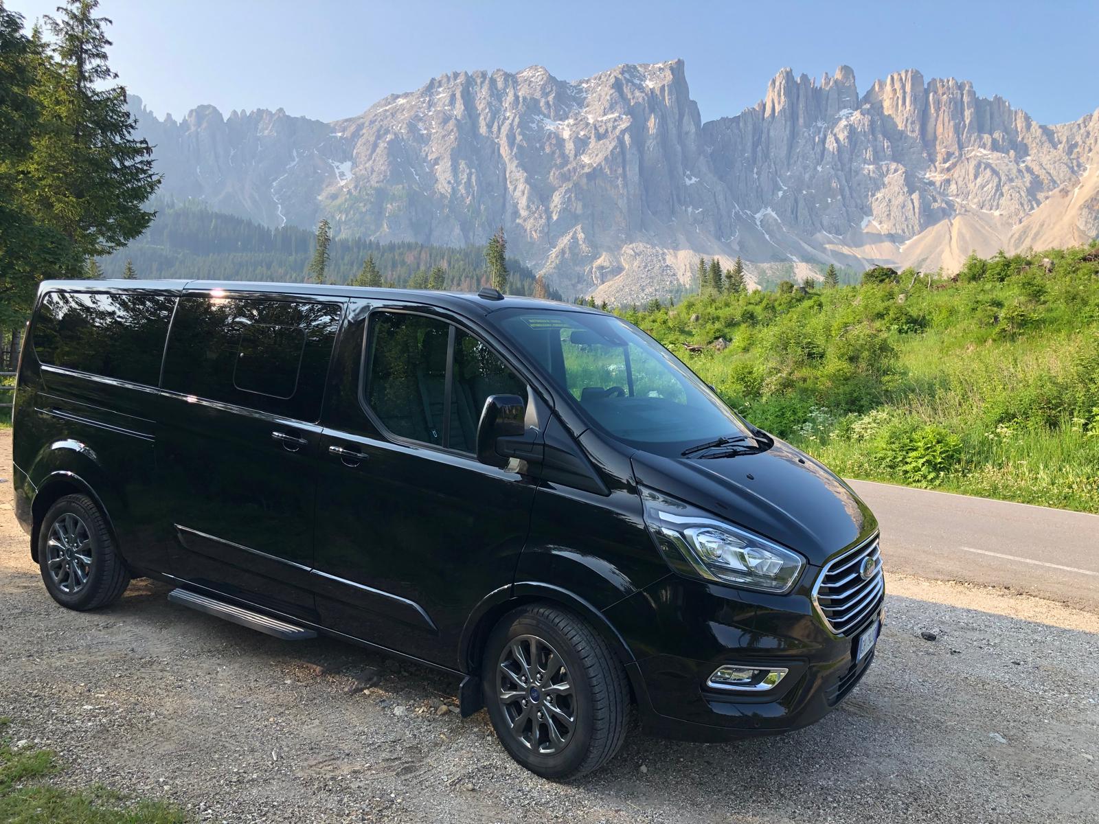 Professional chauffeur opening car door for passenger at Bolzano airport