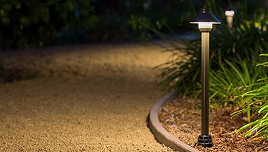 Stone pathway winding through a manicured garden, elegantly lit by low-profile path lights