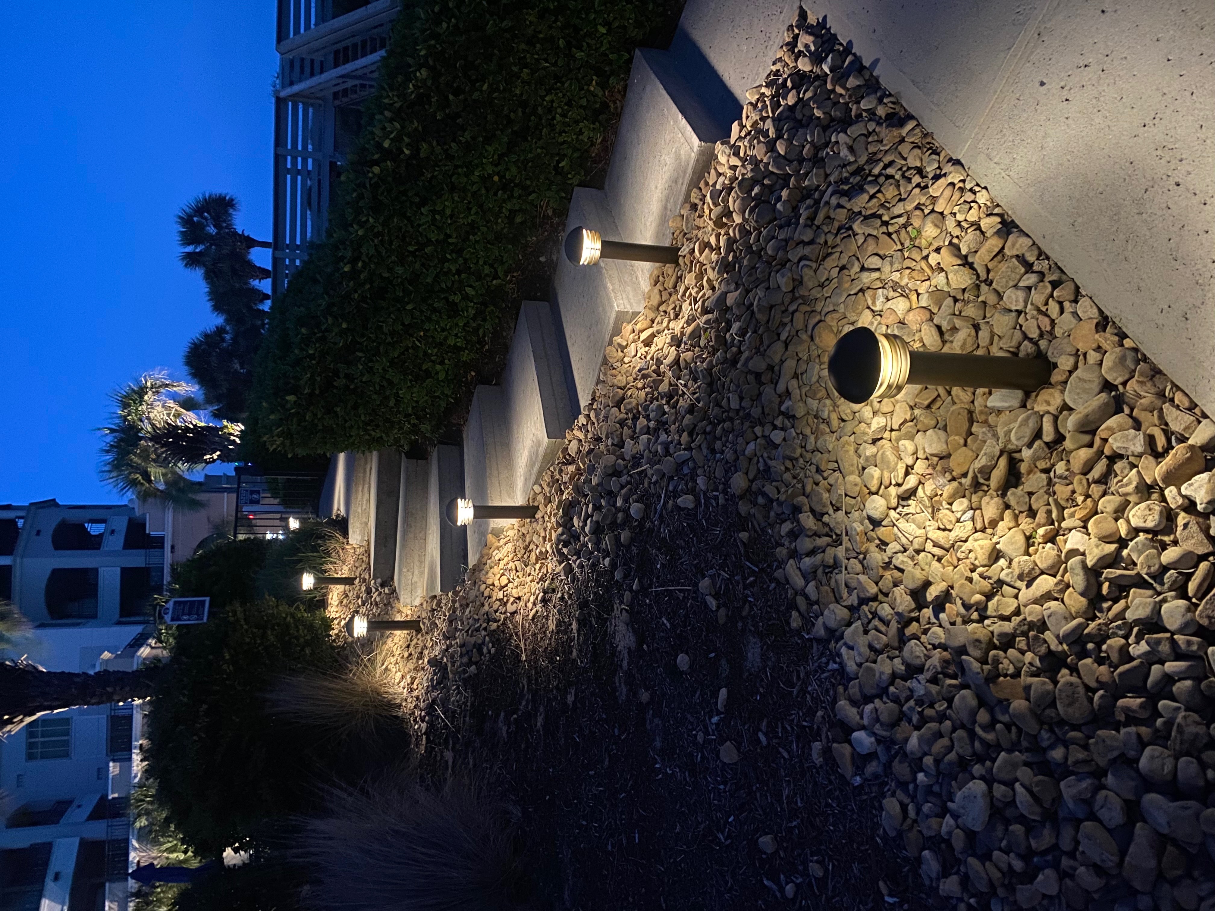 Elegant coastal front entrance with warm downlighting and illuminated palm trees at dusk