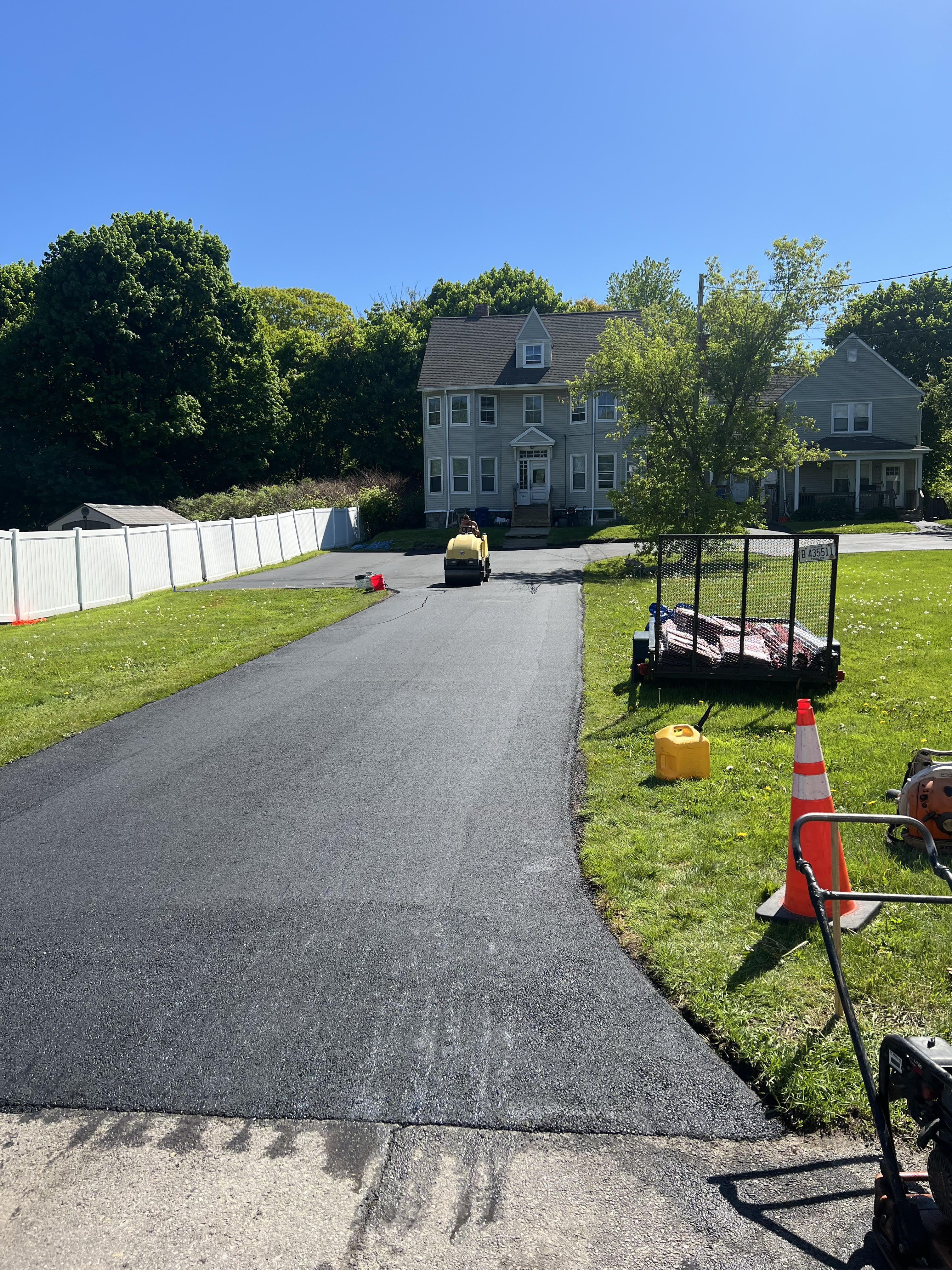 A newly paved, smooth black asphalt residential driveway in a Maine suburban home setting