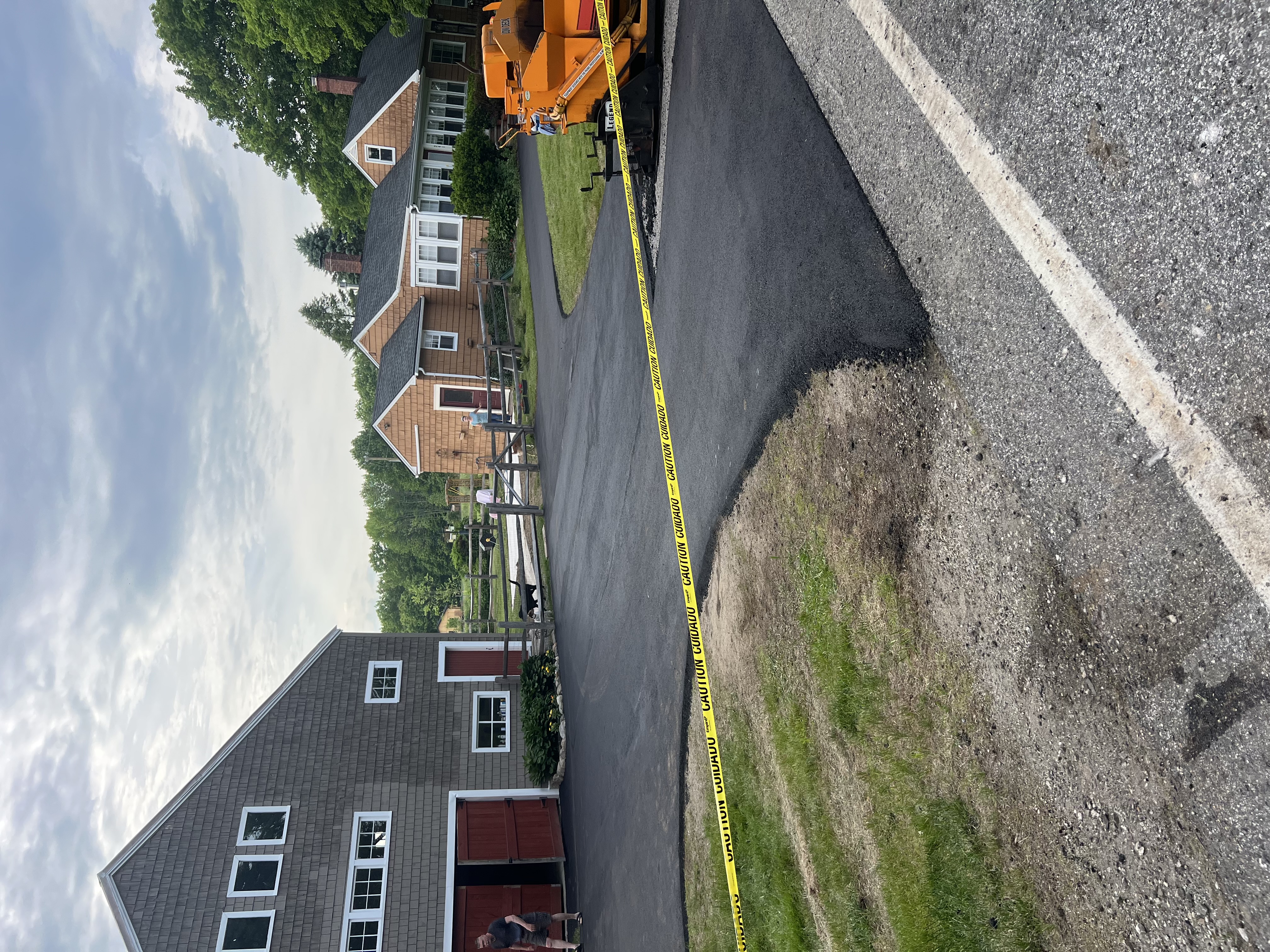 Glossy black asphalt sealcoating application on suburban driveway