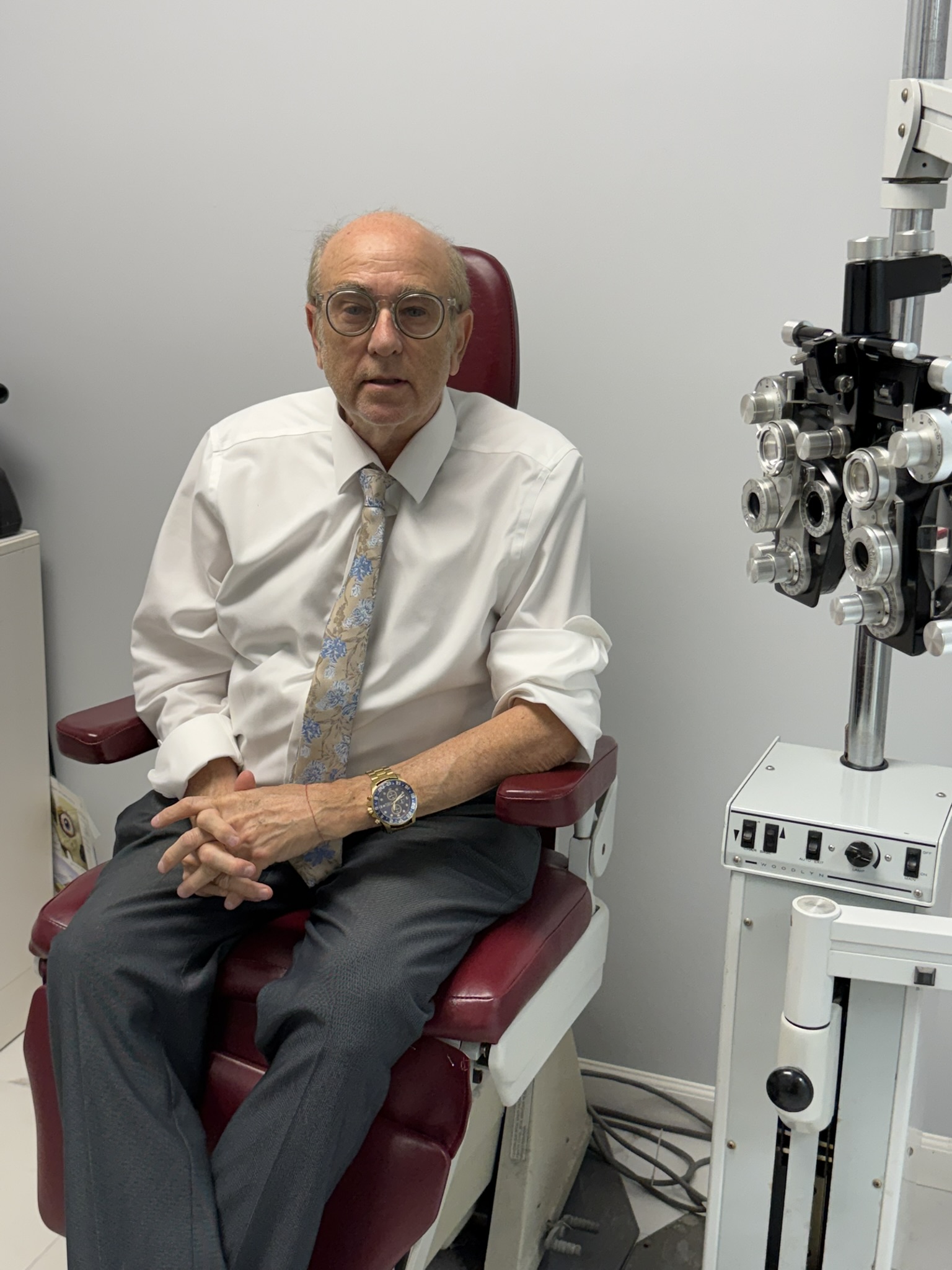 Dr. Jeffrey Hilowitz, lead optometrist at Best Vision Optical, inside the store with designer eyewear on illuminated wooden shelves