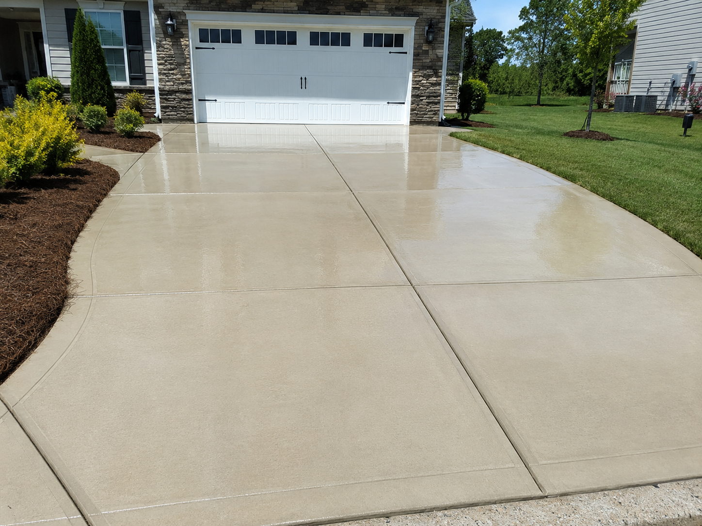 A pristine concrete driveway after being professionally pressure washed, showing a stark clean contrast