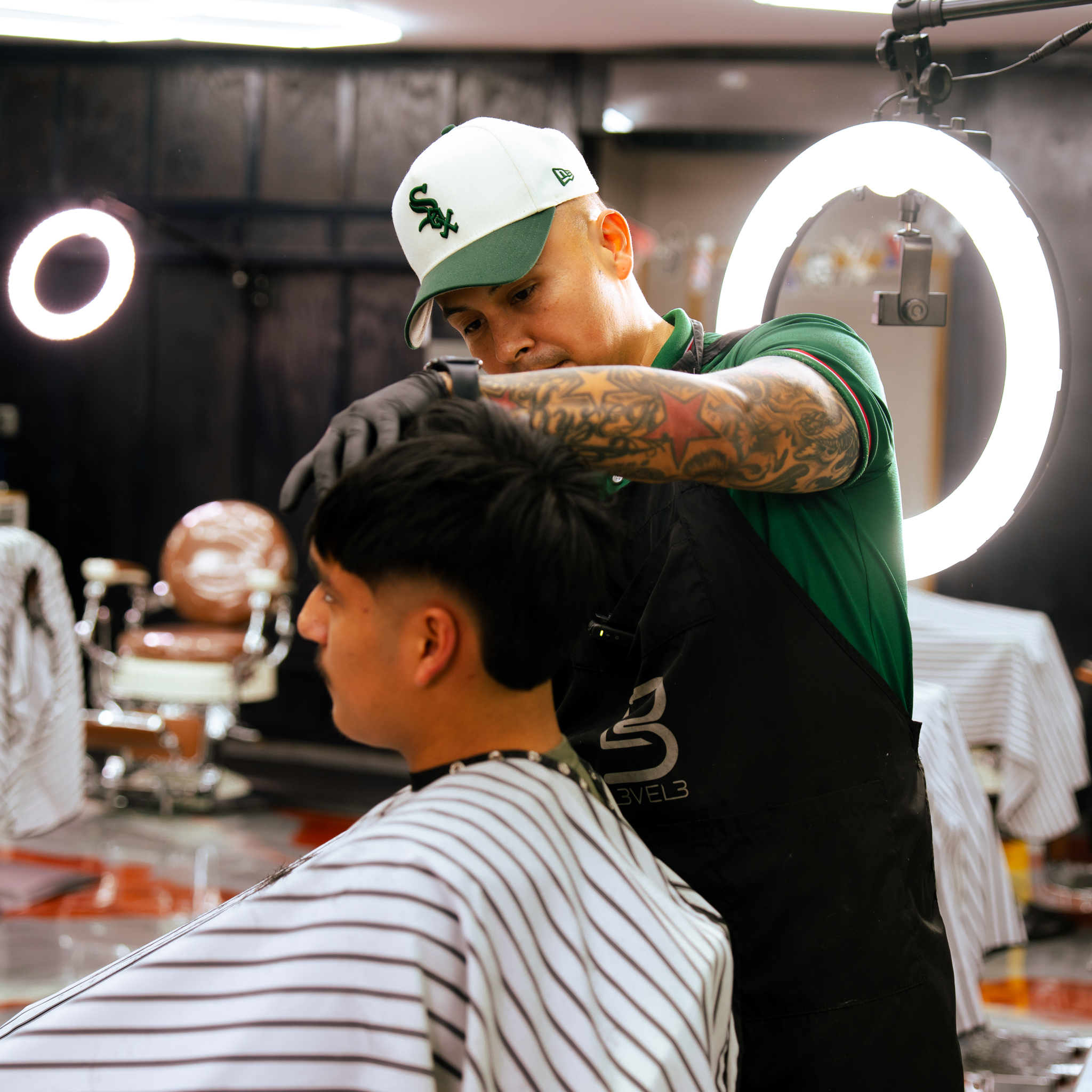 Master barber at Blessed VIP Cutz posing confidently in his black barber apron.