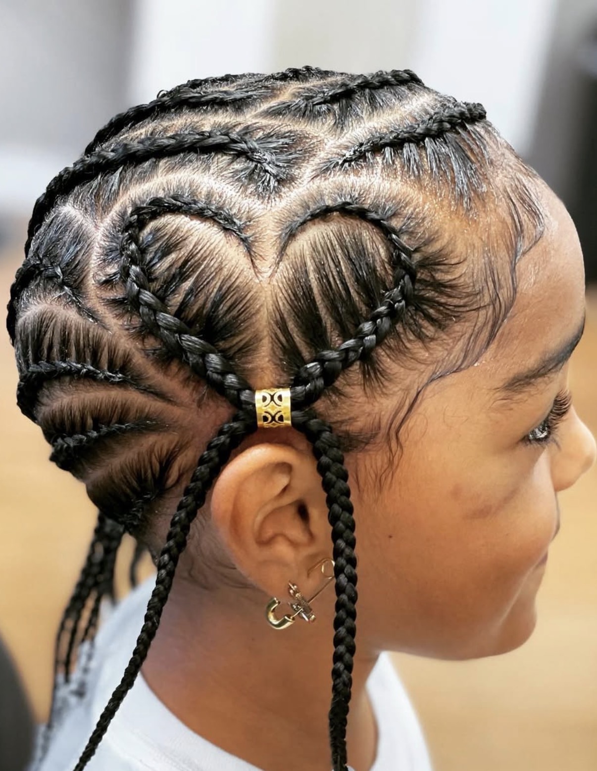 Hairstylist Patrii skillfully creating intricate knotless braids on a client in a warm modern luxury salon