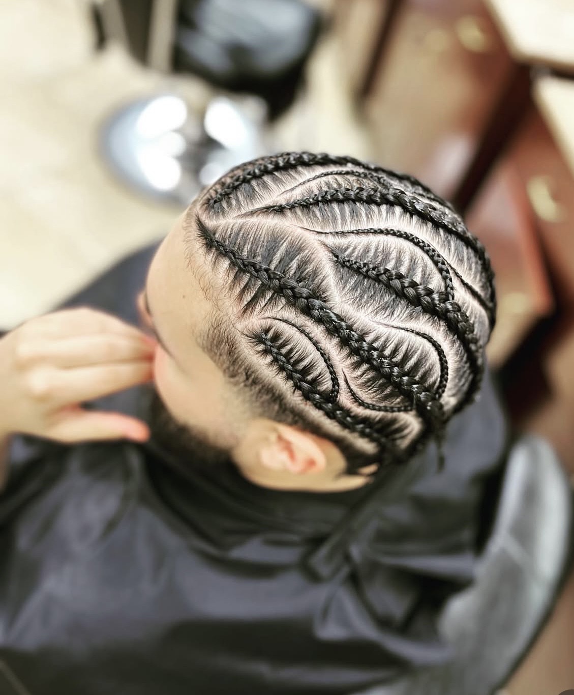 Intricate freestyle cornrow pattern featuring swirl designs on a female client's head
