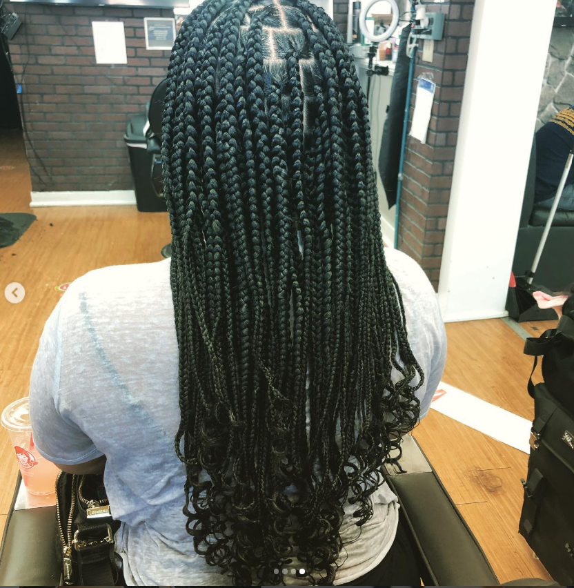 Long waist-length knotless braids styled on a client sitting elegantly in a salon chair