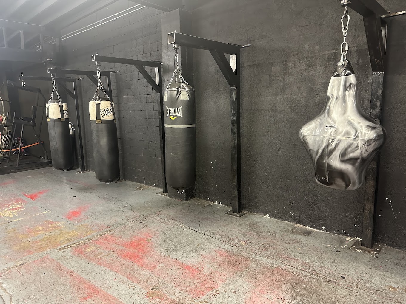 Muscular boxer in red gloves throwing explosive uppercut on heavy bag with sweat flying dramatic side lighting dark gym atmosphere