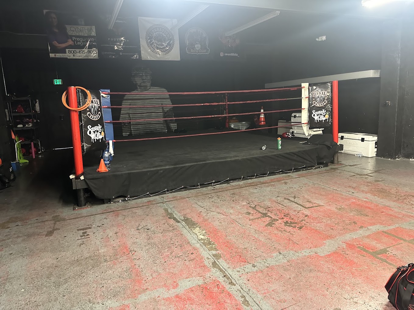 Two amateur boxers sparring in professional boxing ring under bright overhead lights with ropes visible intense competitive moment