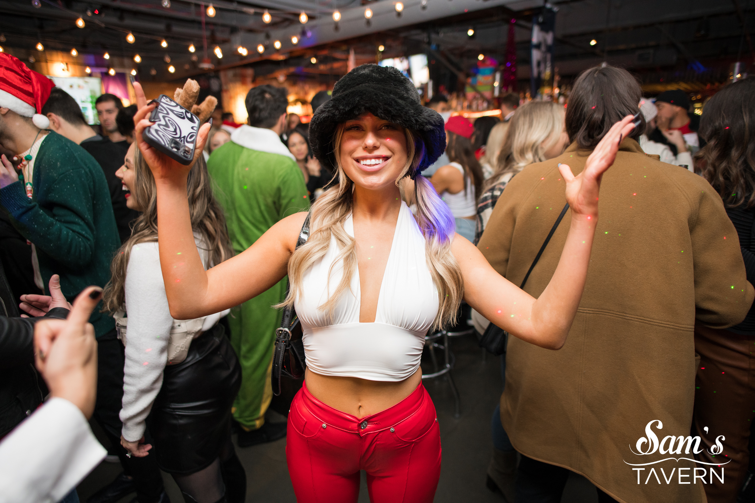 Packed dance floor at a nightclub with red neon lights and a DJ performing