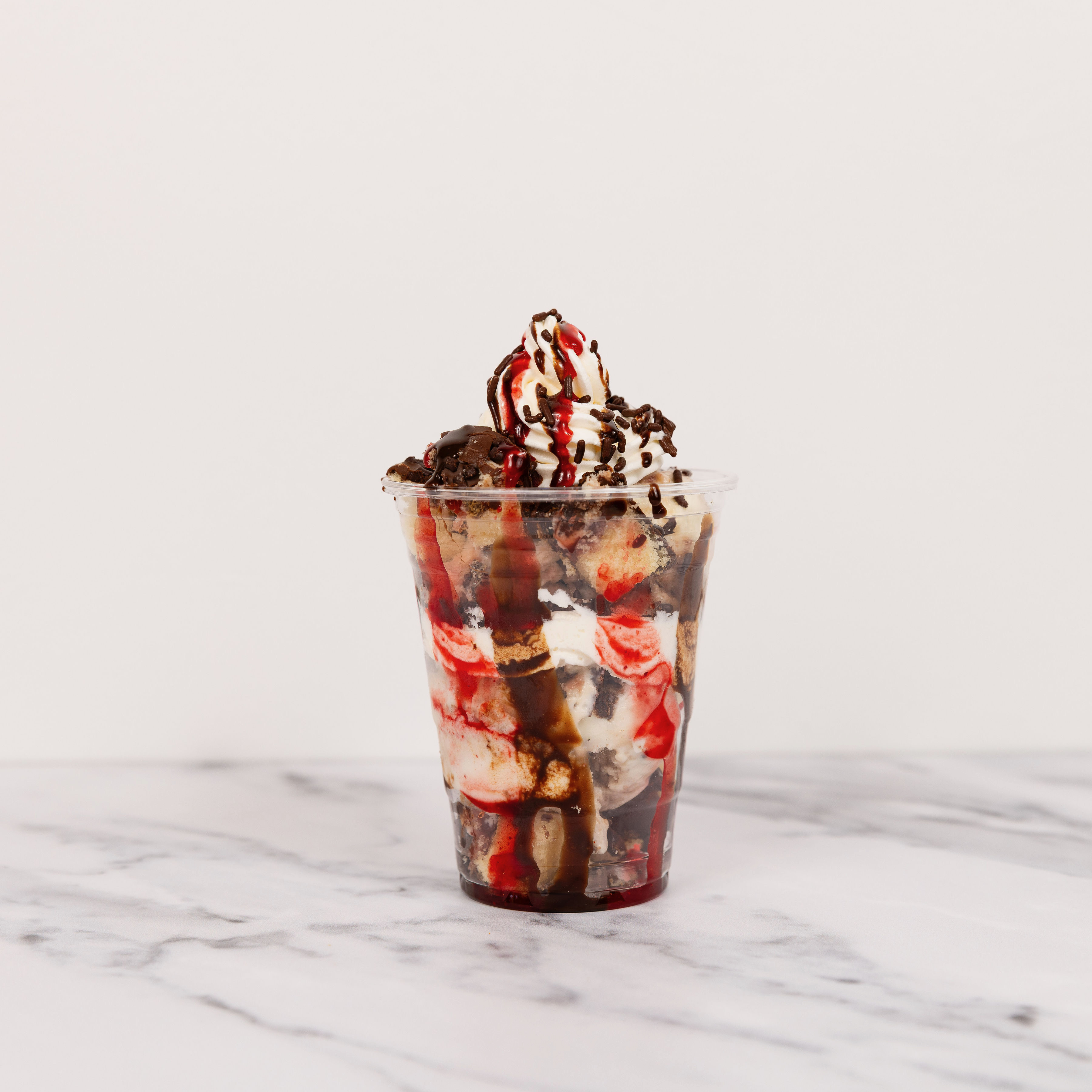 A tall glass layered with fresh strawberries and sweet cream, topped with whipped cream