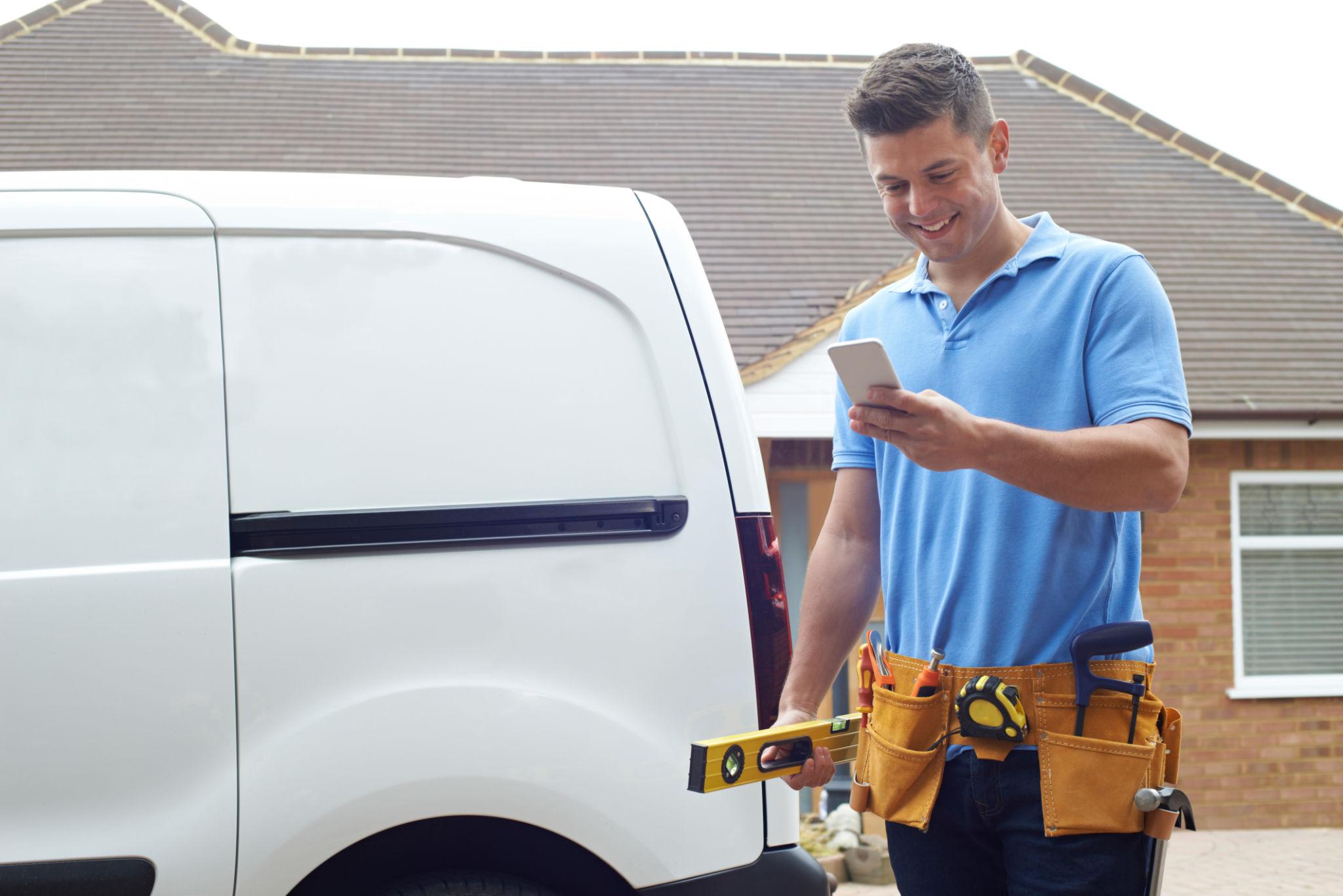 A contractor smiling at new leads on his phone