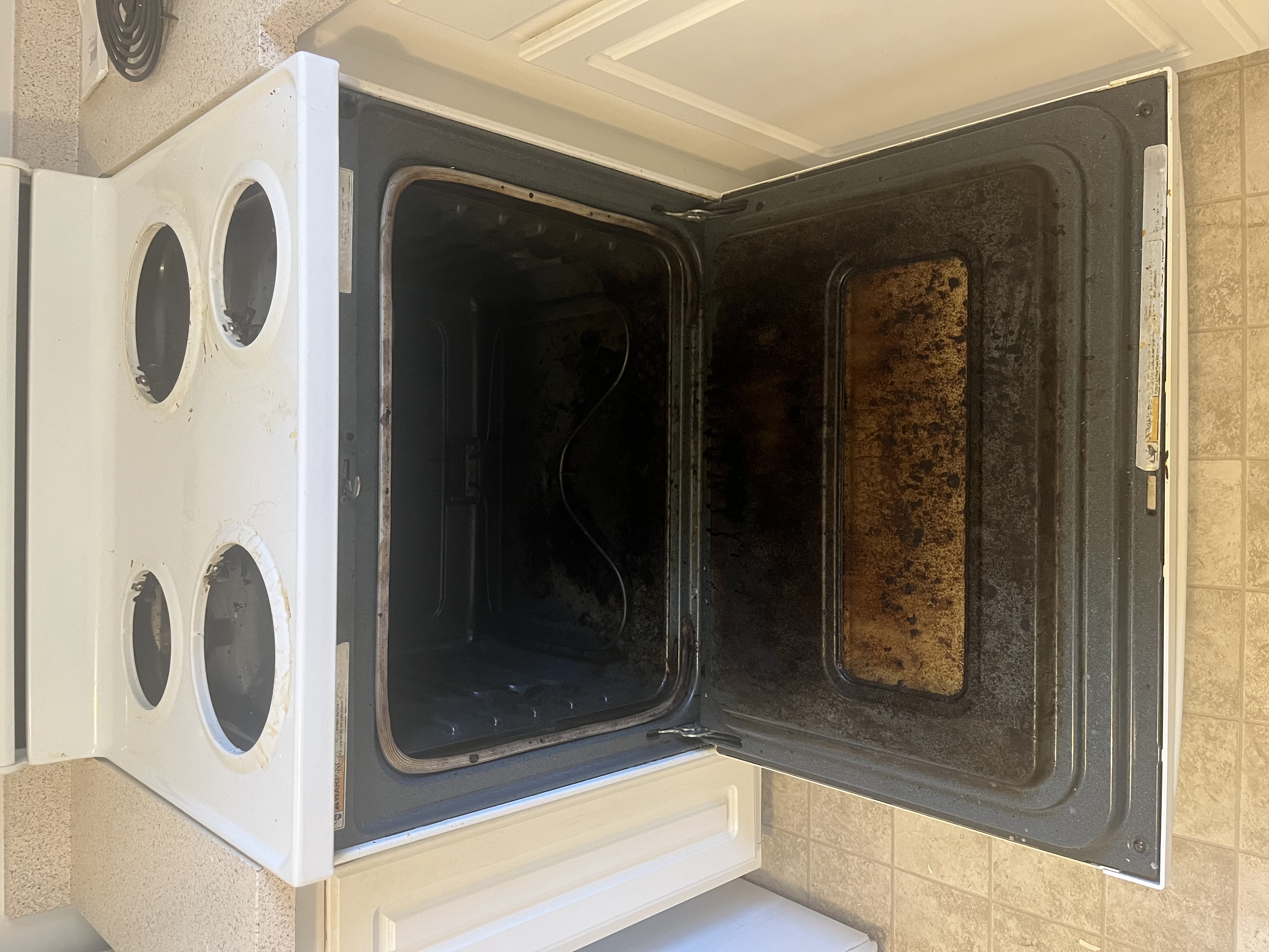 Dirty kitchen with greasy stovetop and cluttered counters before professional cleaning