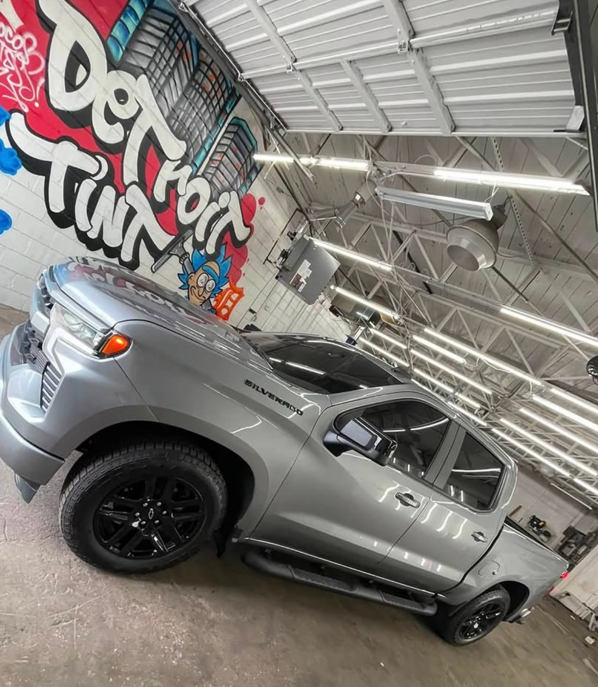 Skilled technician meticulously applying window tint film to a car window in a clean, professional Detroit Tint workshop