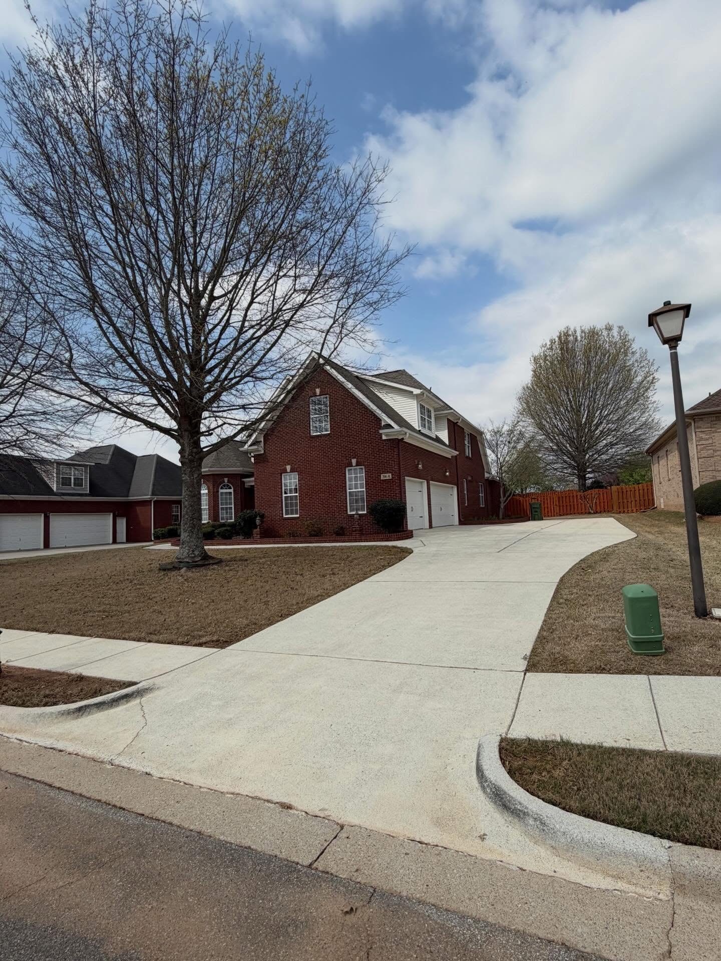 A long concrete driveway covered in dark tire marks and mildew before cleaning.