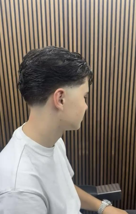 Meester Barbier Kadir staat zelfverzekerd in zijn moderne barbershop in Nederland