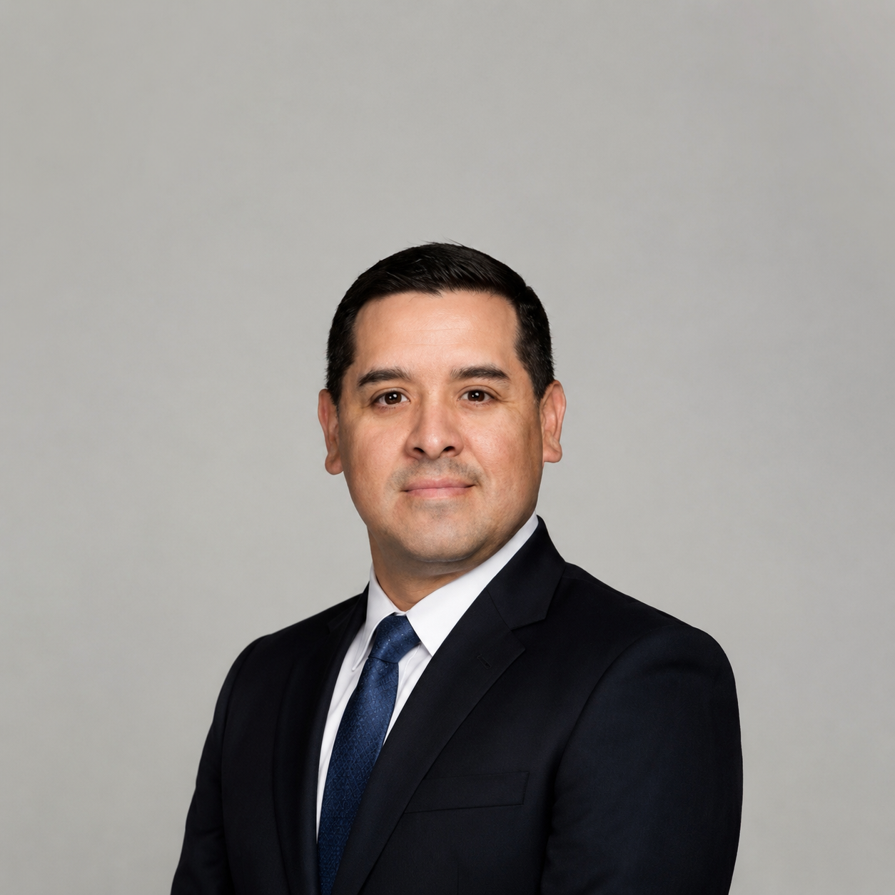 Professional portrait of Marcos Madril, experienced financial advisor and retirement planning host, in business attire