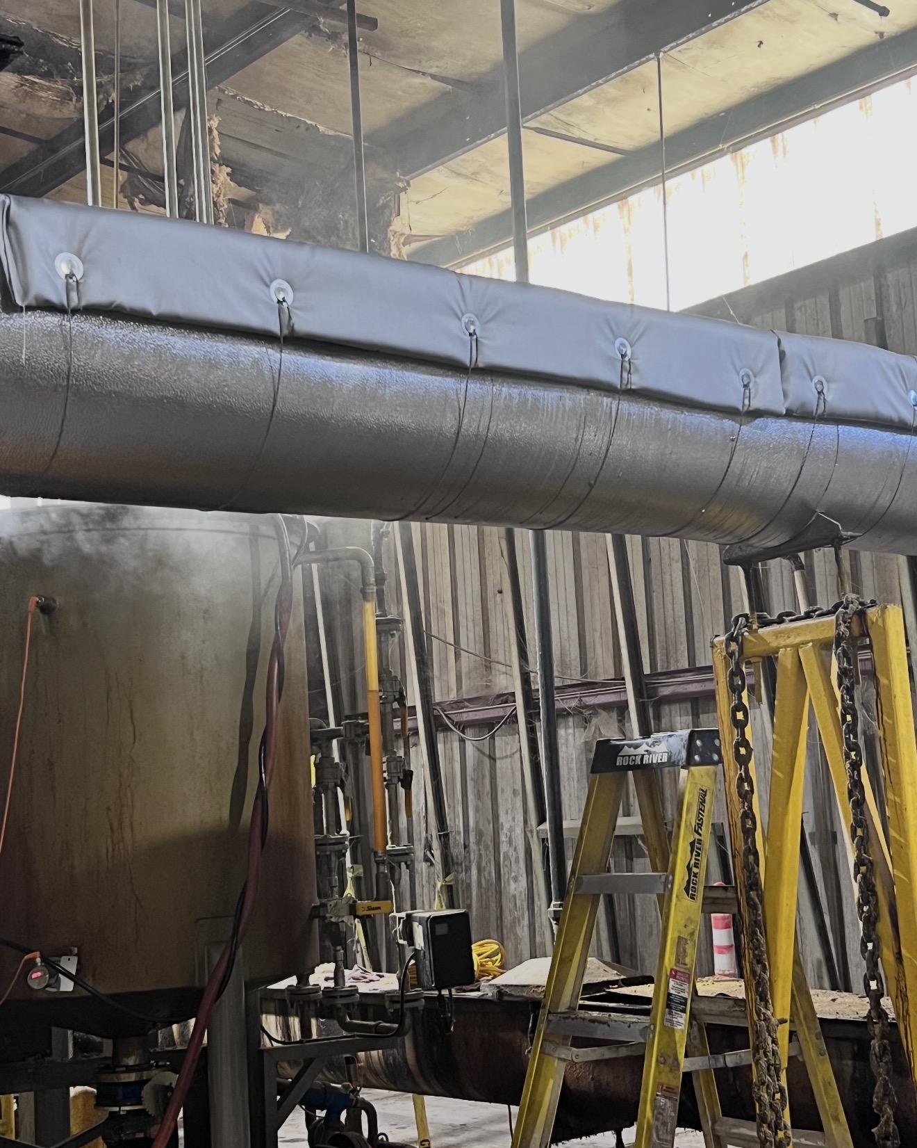 Large shell-and-tube heat exchanger at an oil refinery fully insulated with high-temperature mineral wool and finished with stainless steel cladding for thermal efficiency.