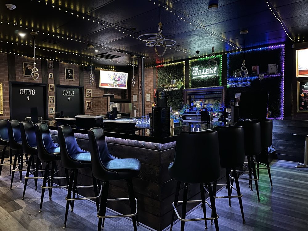 Luxurious LGBTQ+ cocktail lounge interior with glowing neon lighting, gold accents, and energetic nightlife atmosphere at The Gallery Bar