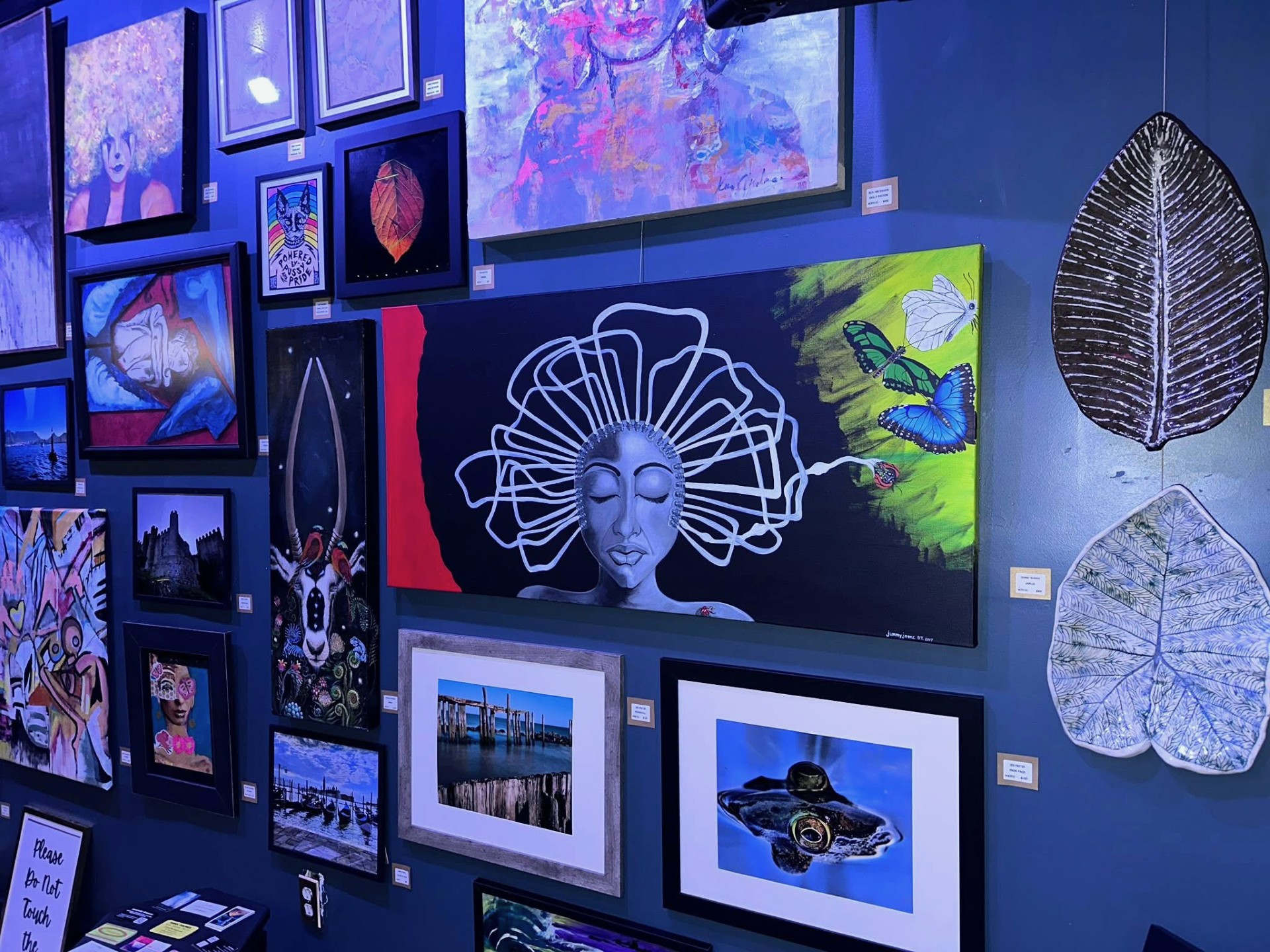 Colorful queer art gallery wall featuring vibrant paintings and contemporary LGBTQ+ artwork