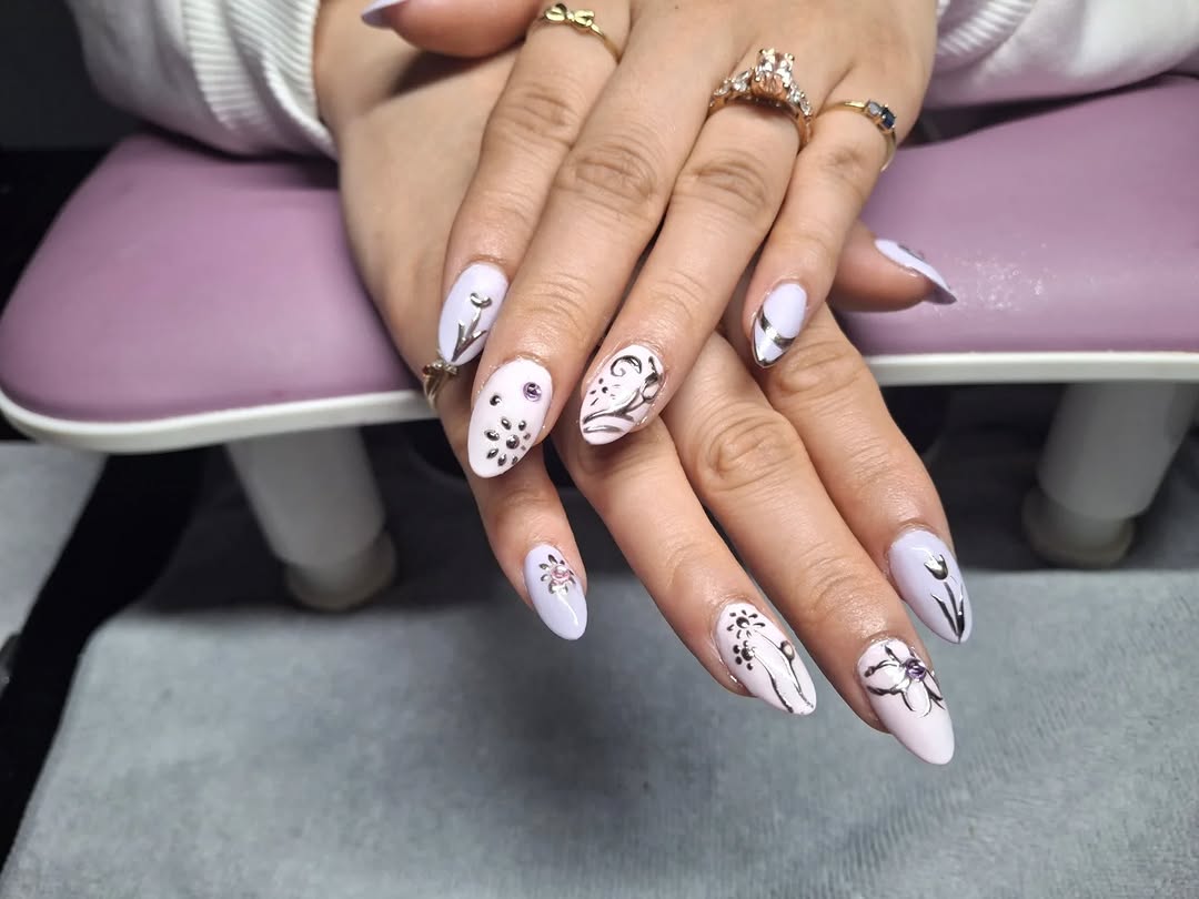 Extreme close-up of a manicured hand resting on a marble nail table with premium polish bottles and rose gold nail tools in Carissa's studio.