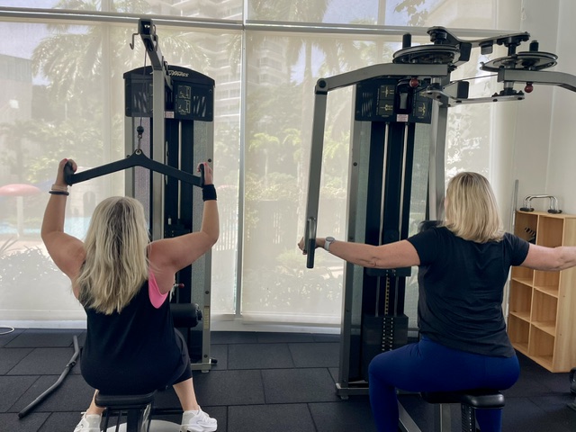 Private gym workout with dumbbells and female coach providing hands-on guidance