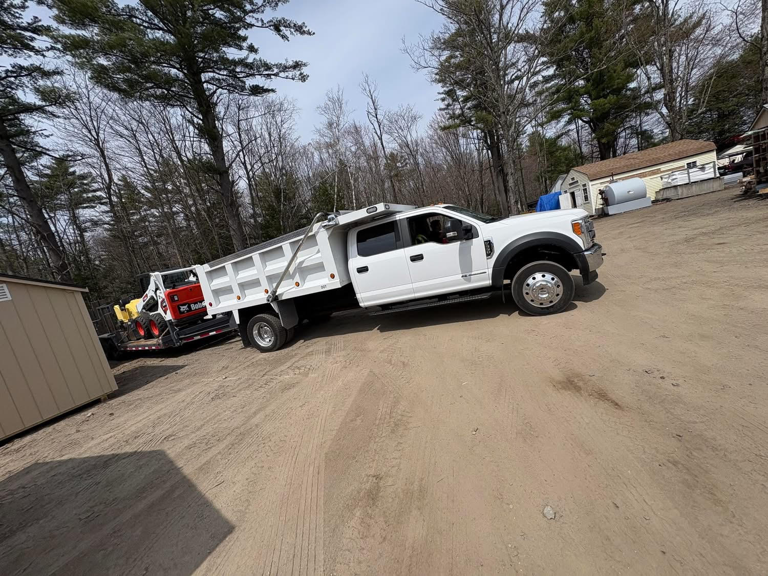 Heavy machinery laying fresh black asphalt for a new driveway in Maine