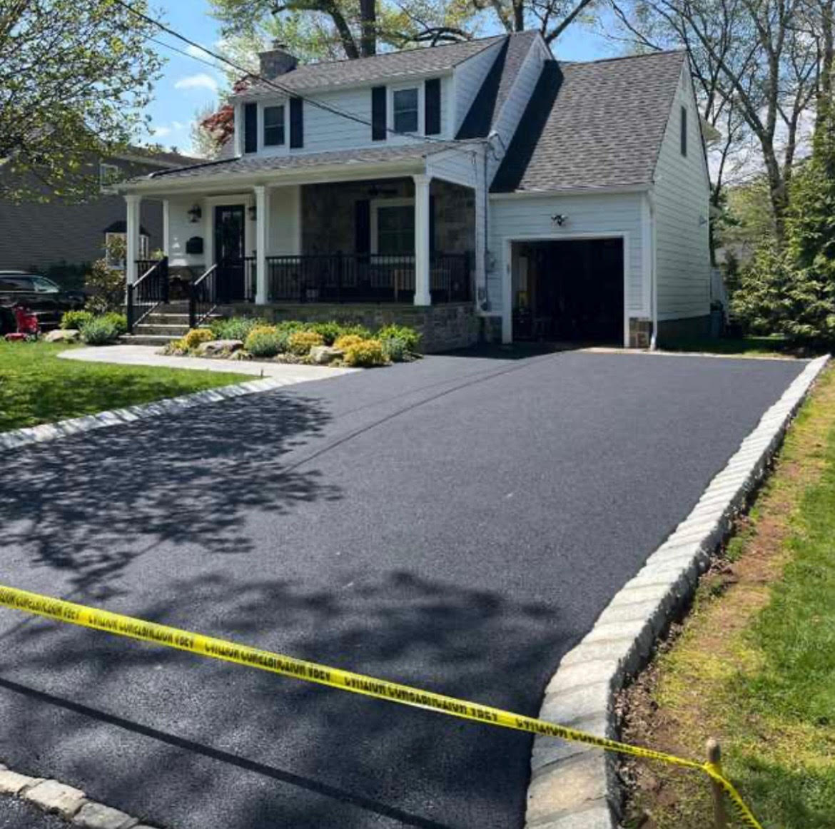 Freshly paved residential asphalt driveway in suburban Maine