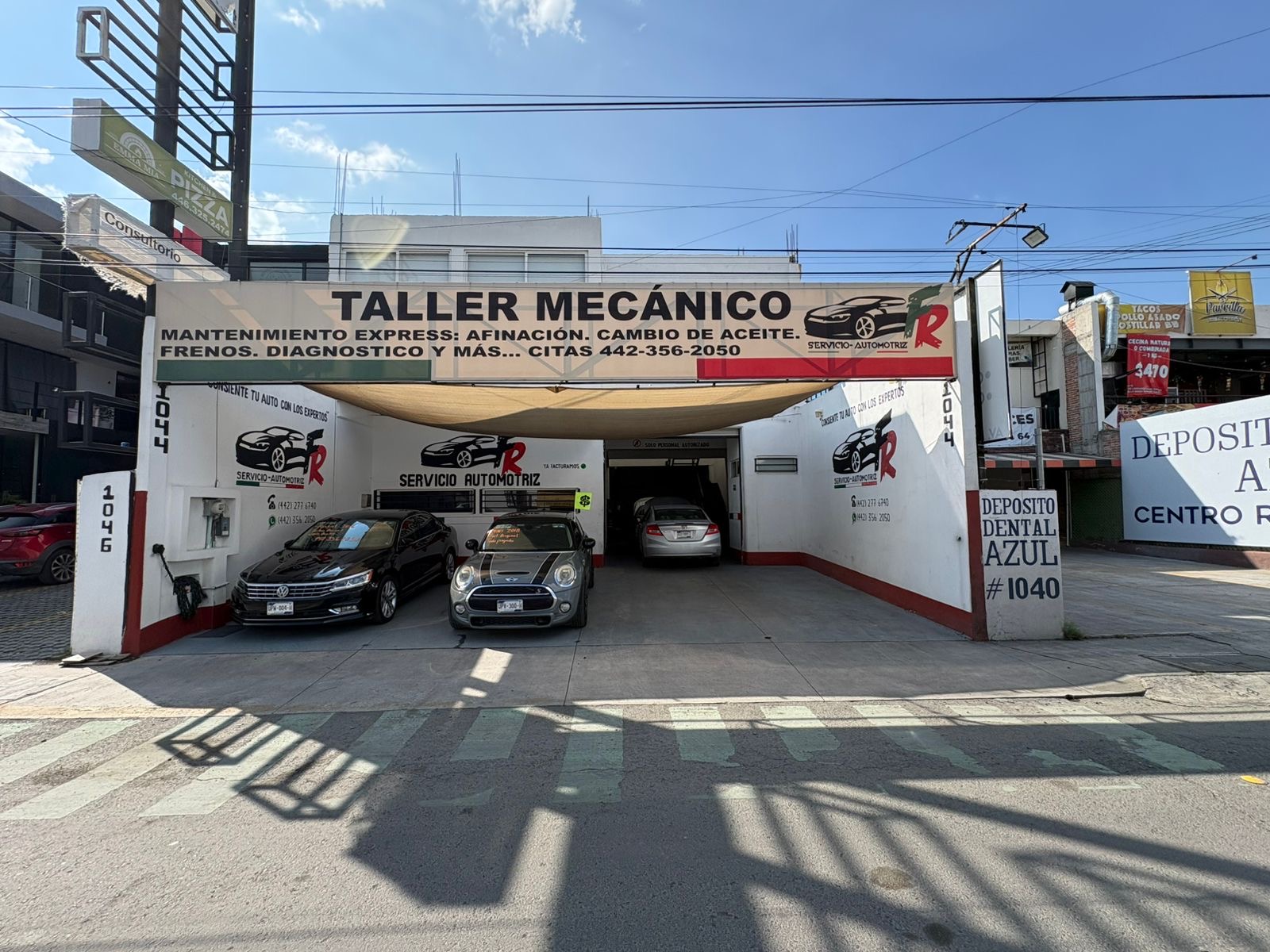 Interior de un taller mecánico moderno, impecable y bien iluminado con rampas hidráulicas rojas y un auto de lujo siendo reparado