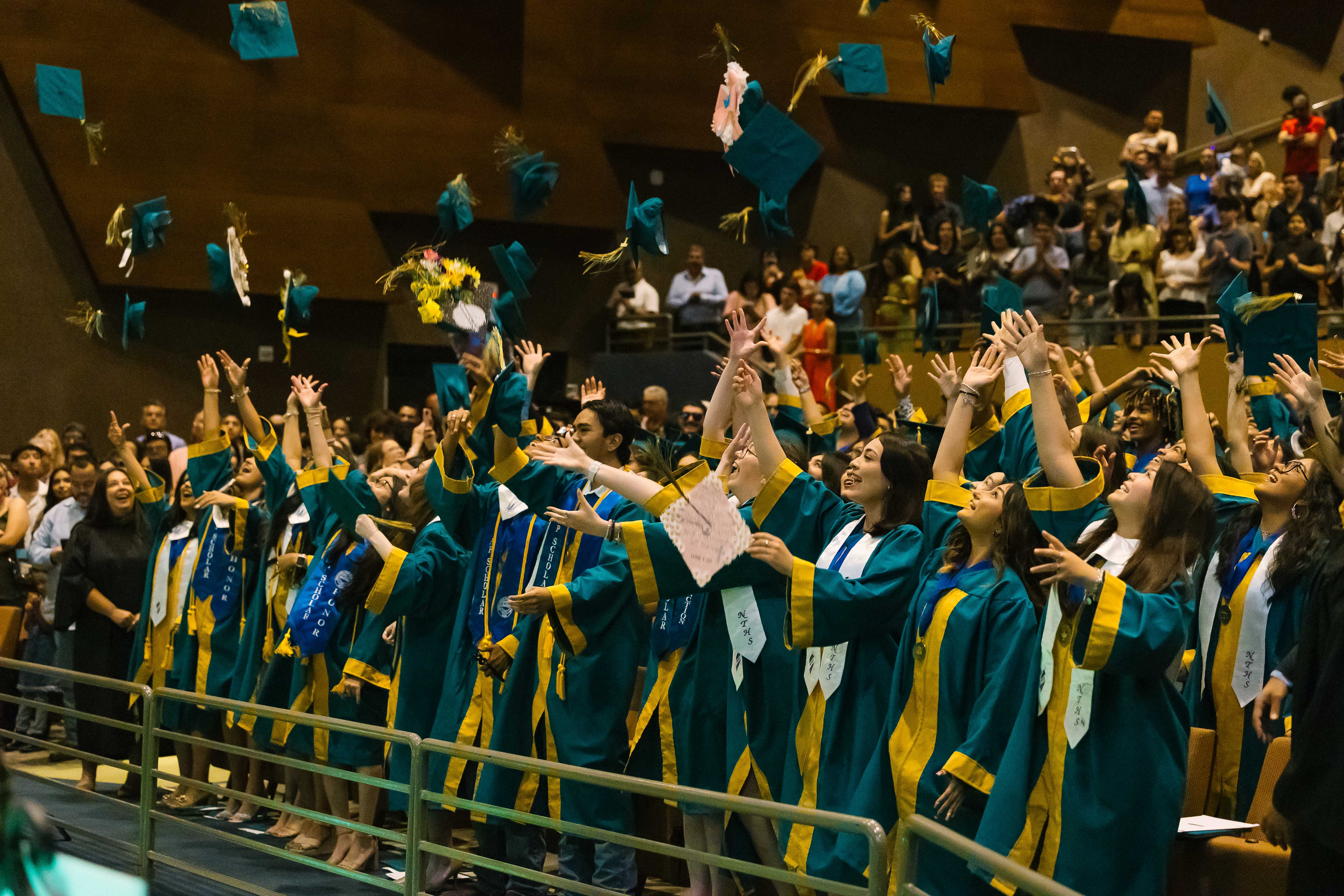 Graduating high school students in caps and gowns celebrating with diplomas