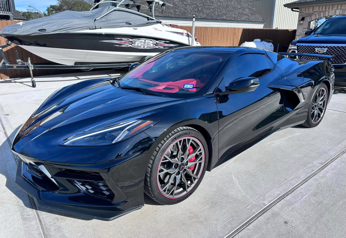 Glossy black luxury sports car with flawless ceramic coating and water beads in a dark cinematic studio