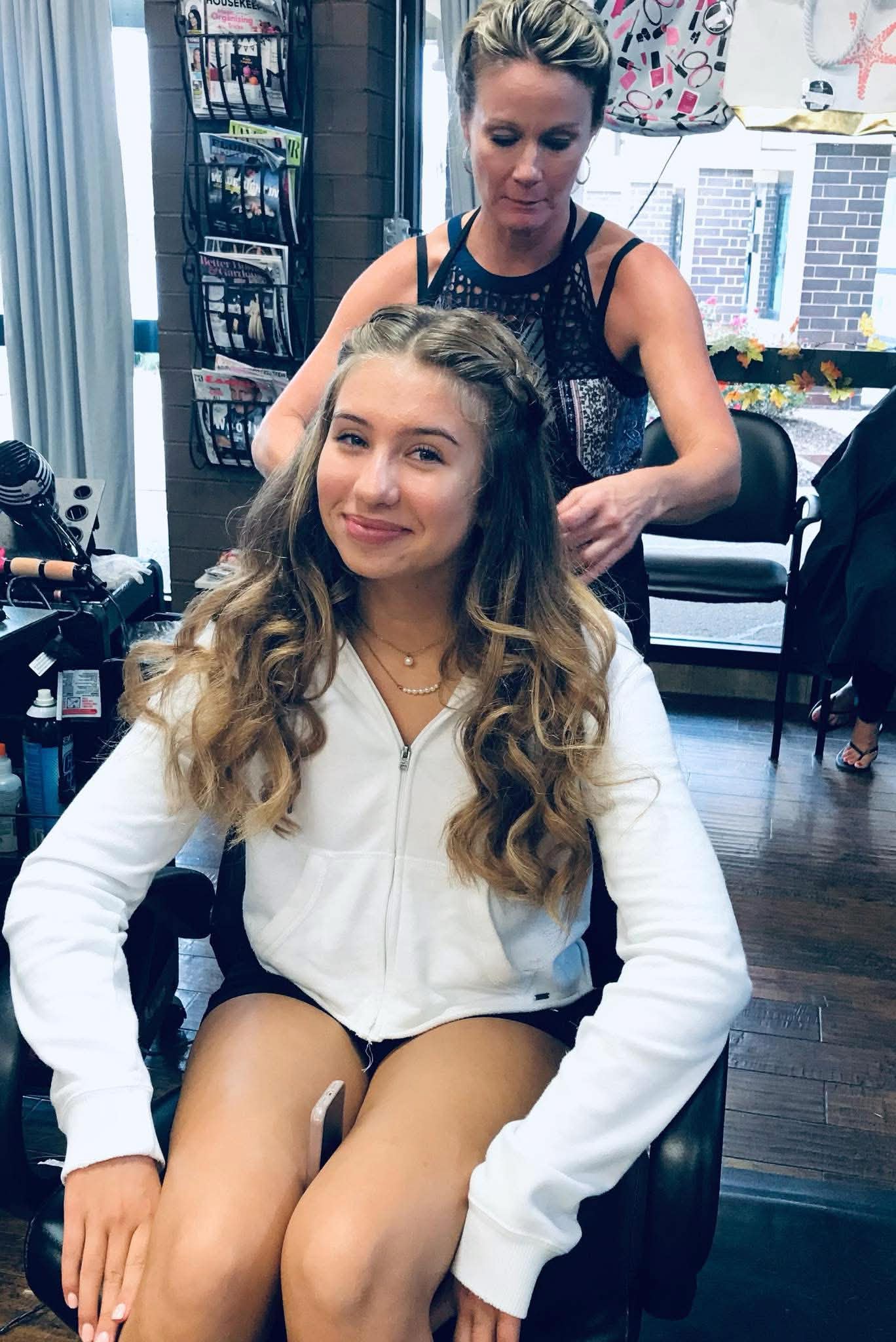 Elegant luxury beauty salon interior with professional stylist working on client's hair in warm ambient lighting at SalonQ Downers Grove
