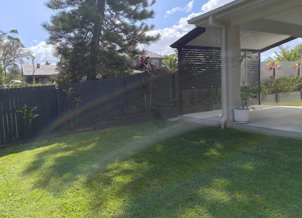 A perfectly manicured residential lawn with sharp edges and vibrant green grass next to a pristine garden bed
