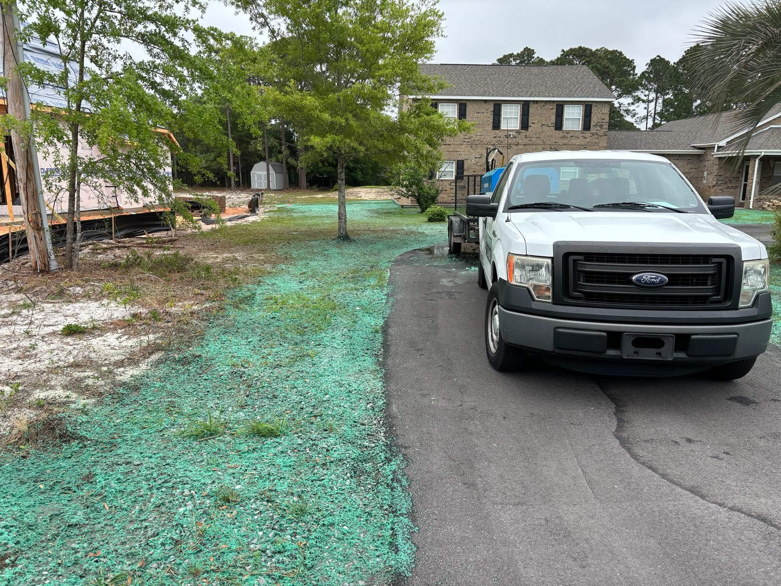 Professional hydroseeding equipment truck spraying green seed slurry onto freshly prepared soil for new lawn establishment