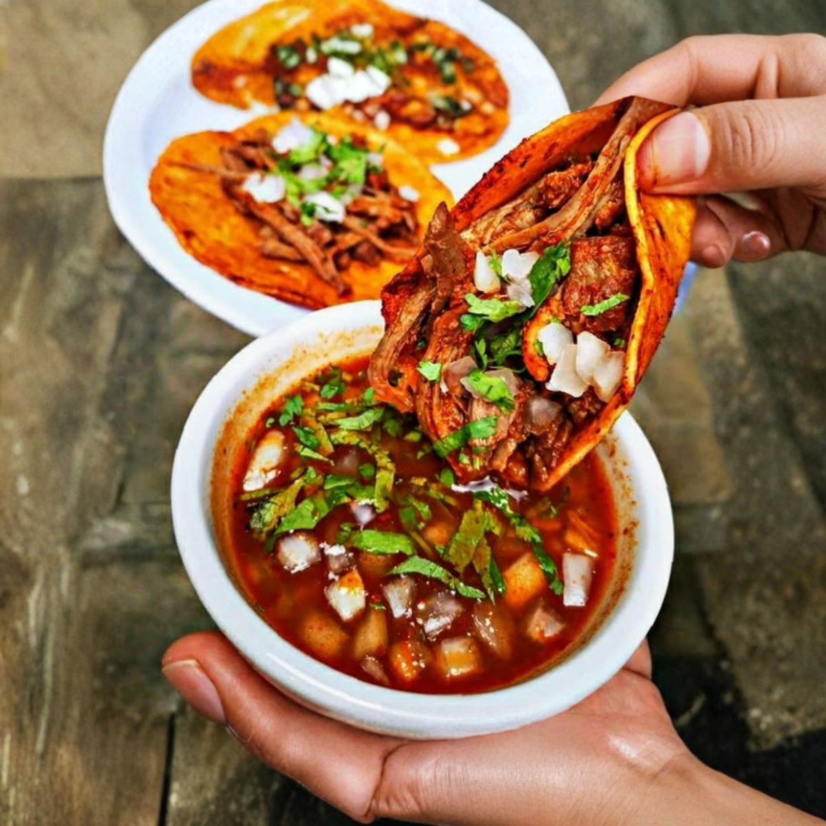 A close-up of a crispy quesabirria taco overflowing with melted cheese and juicy meat