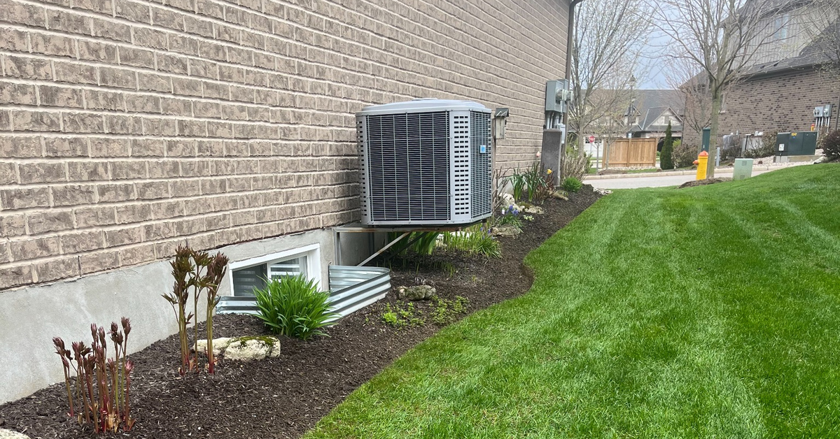 Fresh dark mulch installed around trimmed shrubs and flower beds at an Acton Ontario residential home