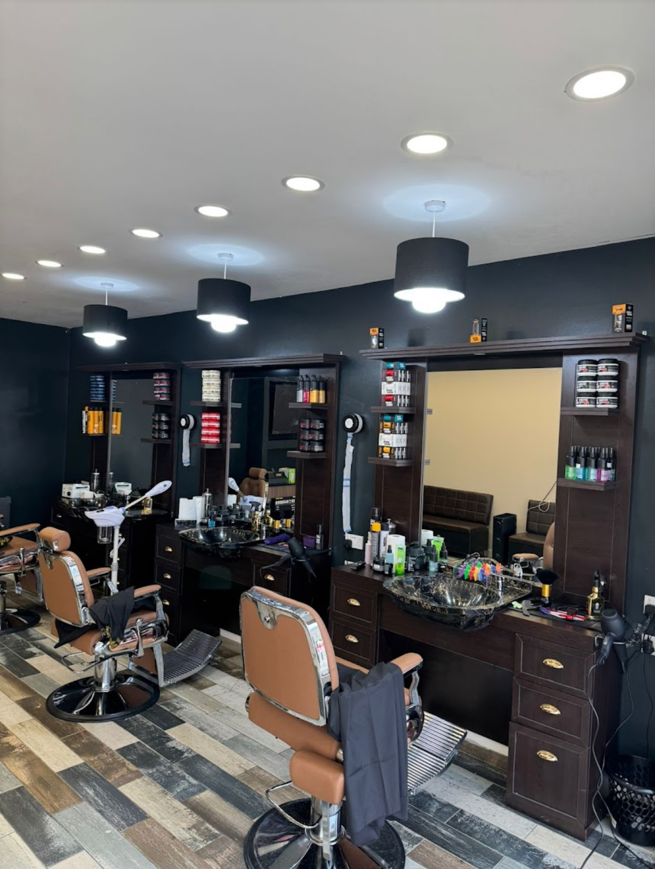 Master barber executing a precision skin fade haircut on a male client in a moody, dimly lit vintage urban barbershop with leather chairs and warm gold lighting